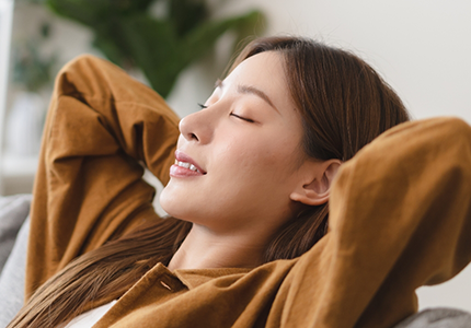 Woman relaxing on a couch with her hands behind her head
