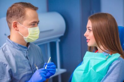 A dentist and woman engage in conversation in a dental clinic setting.