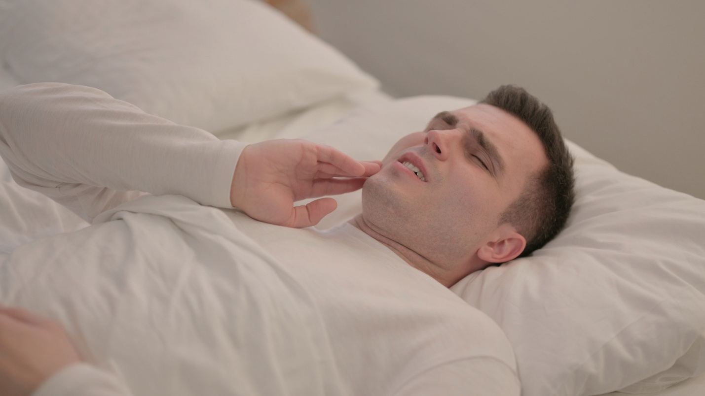 Man lying in bed with a toothache.